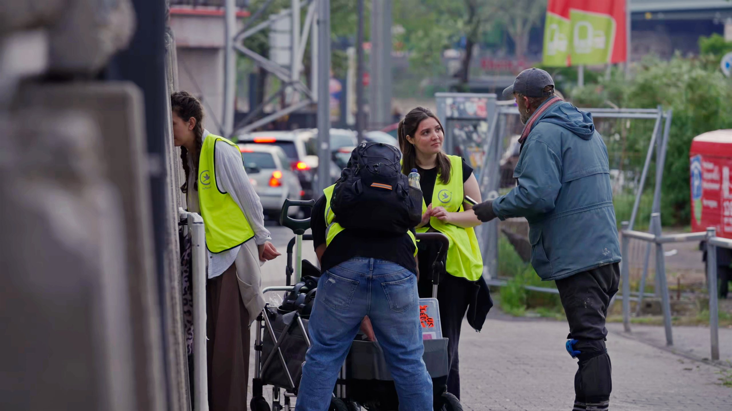 Ehrenamtliche von Hoffnungsvoll in gelben Westen im Gespräch mit Menschen auf einer Straße in Köln